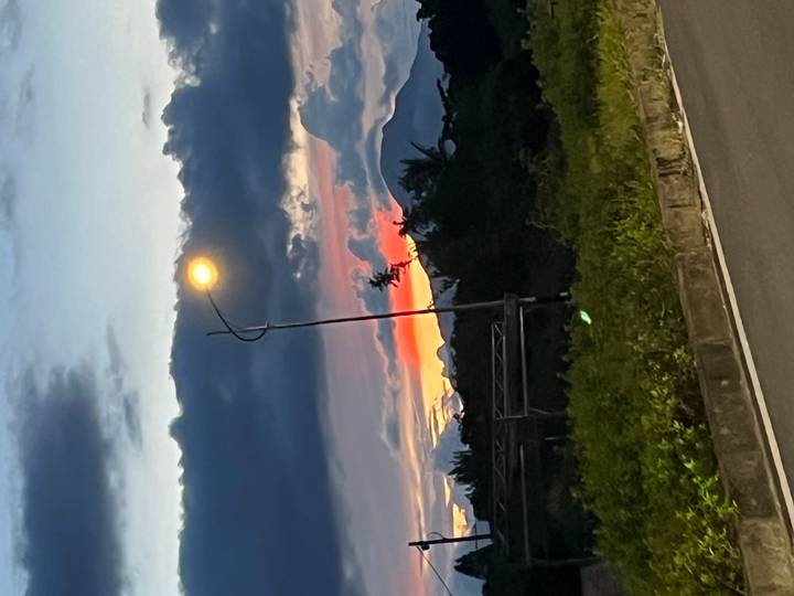 Twilight road scene with single streetlamp and dramatic cloud layers over distant hills.