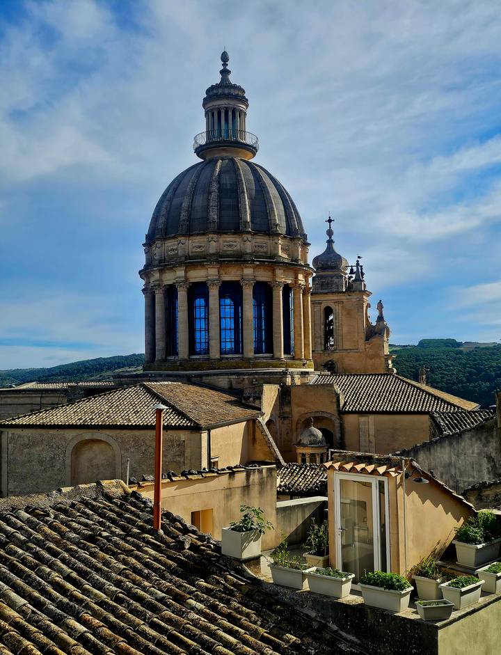Ornate dome and bell tower of the Baroque San Giorgio Cathedral rising above tiled rooftops.