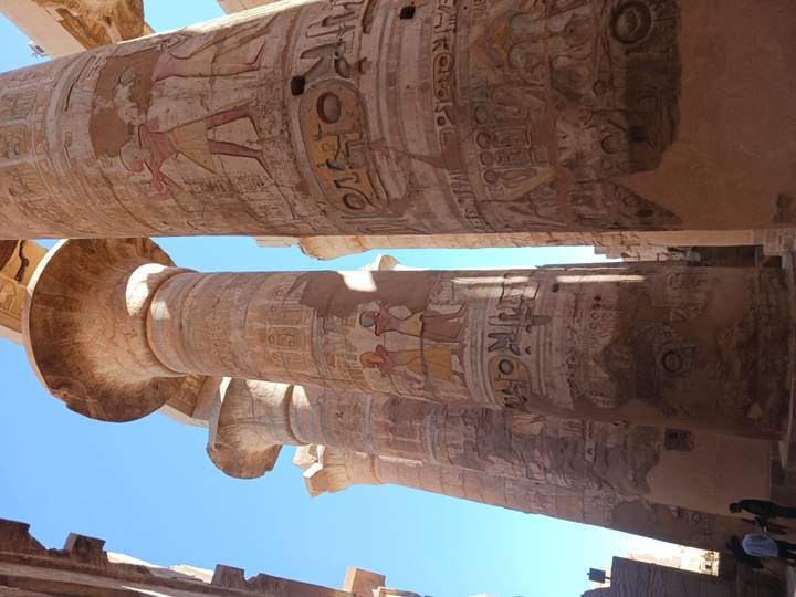 Detailed hieroglyph-covered columns of Karnak Temple bathed in warm sunlight against blue sky.