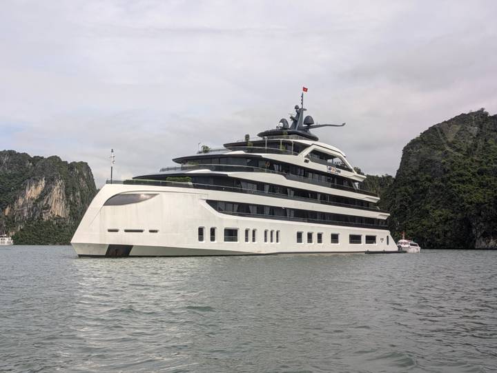 Modern white cruise ship anchored among limestone karsts in tranquil bay waters