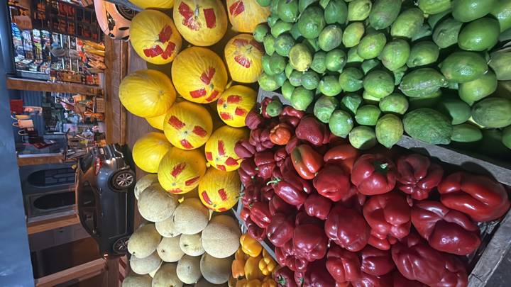Vibrant nighttime market display of peppers, melons and limes on a street stall.