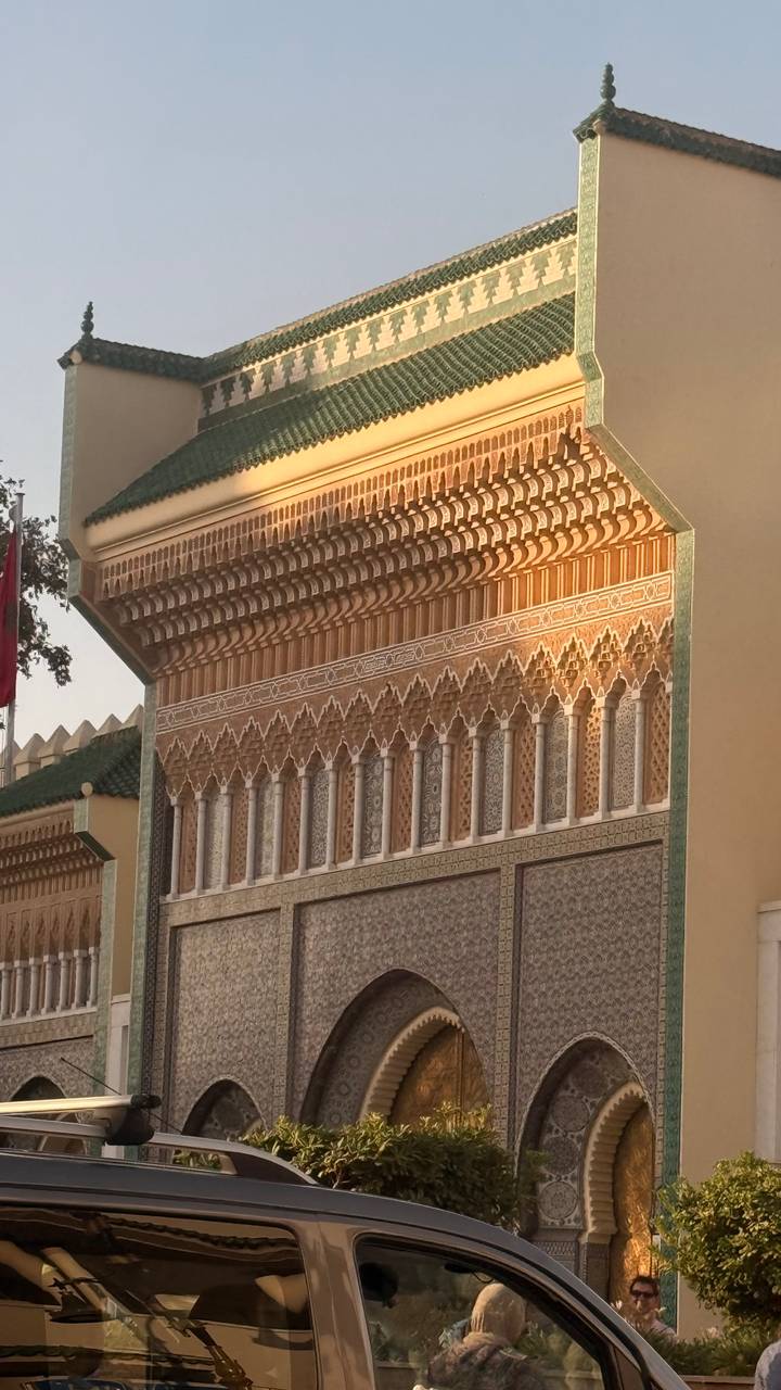Detailed Islamic tile and stucco work on a royal Moroccan façade glowing in late light.