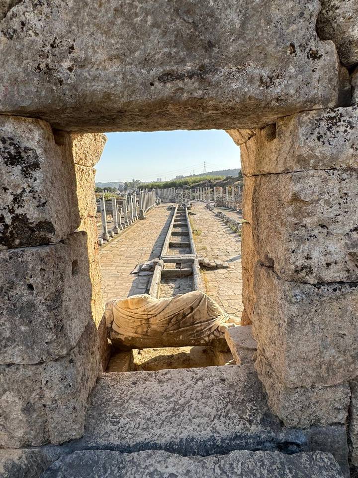 Ancient colonnaded street viewed through a stone archway at the Perga ruins.