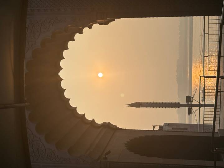 Soft sunrise viewed through an ornate archway overlooking a calm river.