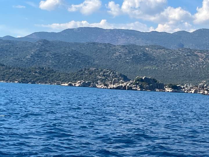 Blue Mediterranean waters with rugged coastal hills in the background.