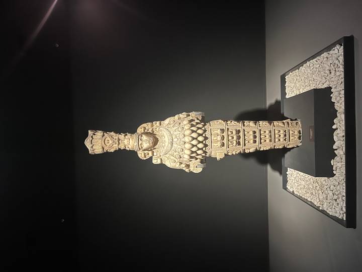 Museum display of the multi-breasted statue of Artemis of Ephesus against a dark background.