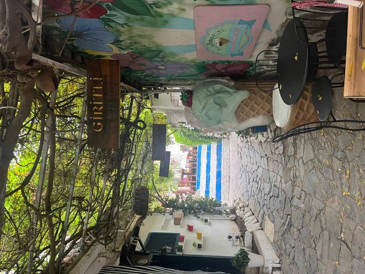 Charming cobblestone alley with grape-covered pergola, colourful signs and an oversized ice-cream sculpture.
