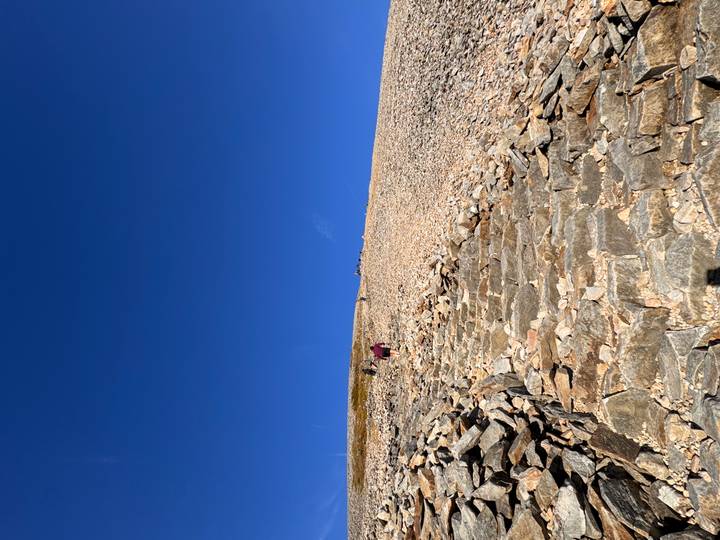 Stone steps ascend a steep, barren mountain slope beneath a vivid blue sky.