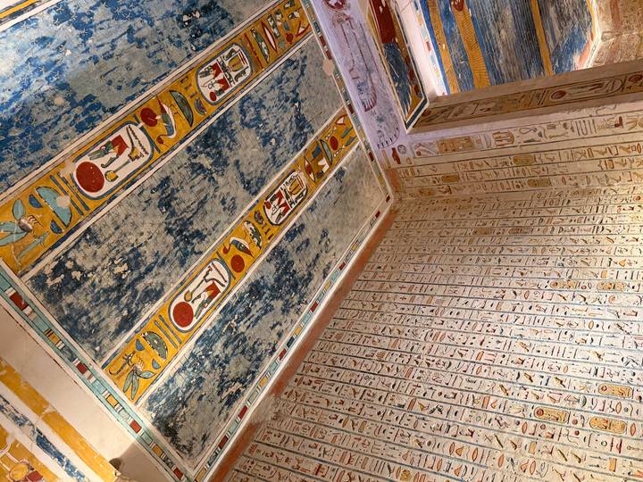 Vibrantly painted hieroglyphic ceiling and walls inside an ancient Egyptian tomb.