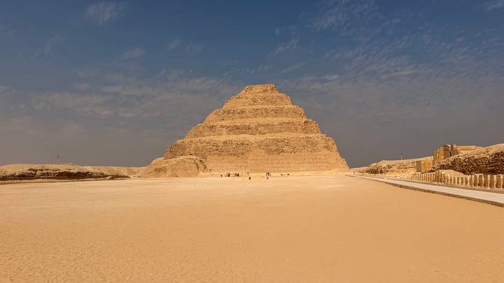 The Step Pyramid of Djoser rises from the desert sands beneath a hazy sky at Saqqara.