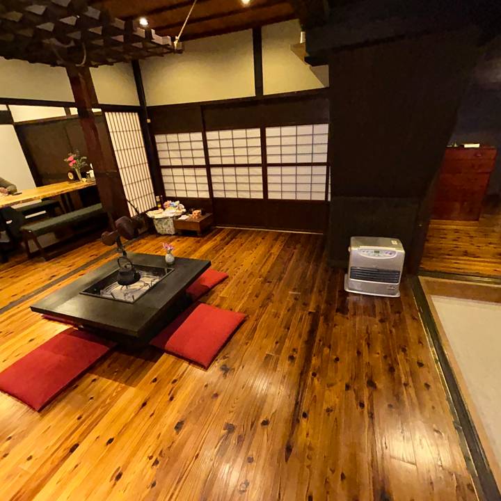 Traditional Japanese ryokan room with low hearth table, red cushions and polished wooden floor.