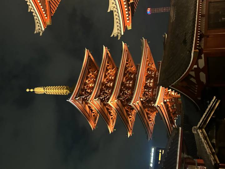 Illuminated five-story pagoda of Senso-ji temple glowing against the night sky.