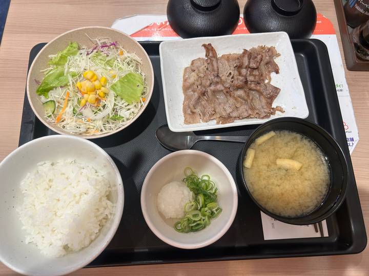 Tray with Japanese set meal including rice, miso soup, grilled beef slices and salad.