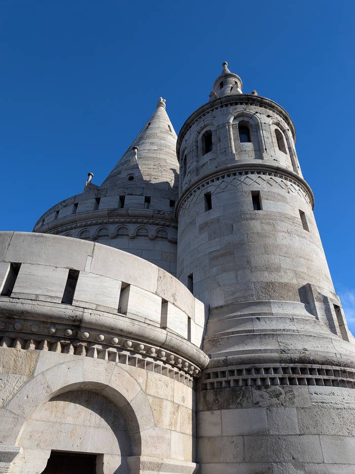 Close-up view of a stone turret and walls of Fisherman’s Bastion under blue sky.
