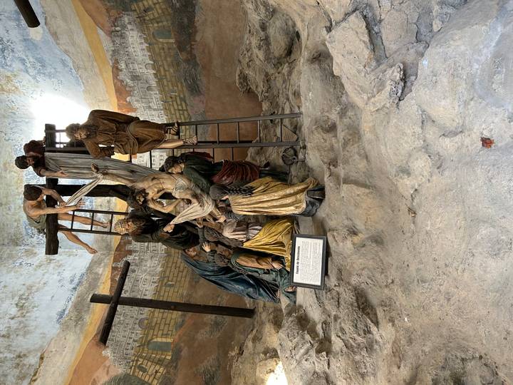 Life-size sculptural tableau depicting the Deposition of Christ inside a stone chapel setting