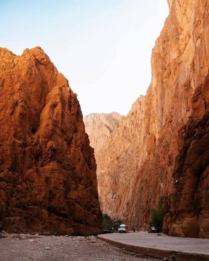 Towering rust-coloured canyon walls of Todra Gorge under bright sky