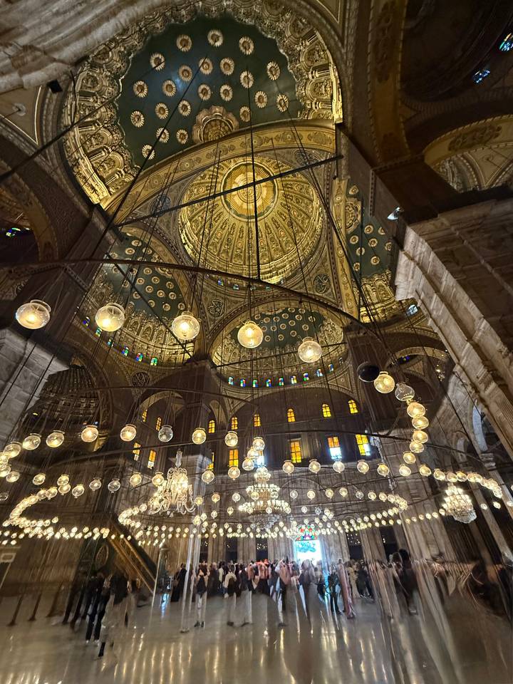 Lavish interior dome of Muhammad Ali Mosque with ornate gold patterns and hanging lamps