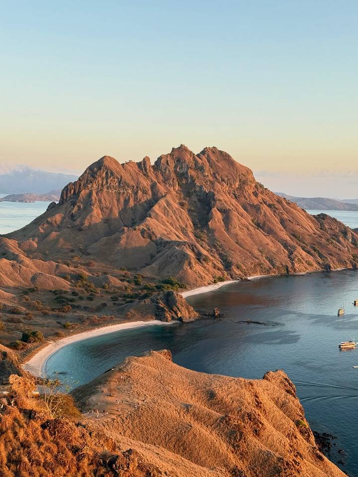 Spectacular aerial view of the rugged orange ridges and surrounding turquoise bays of Padar Island at golden hour.