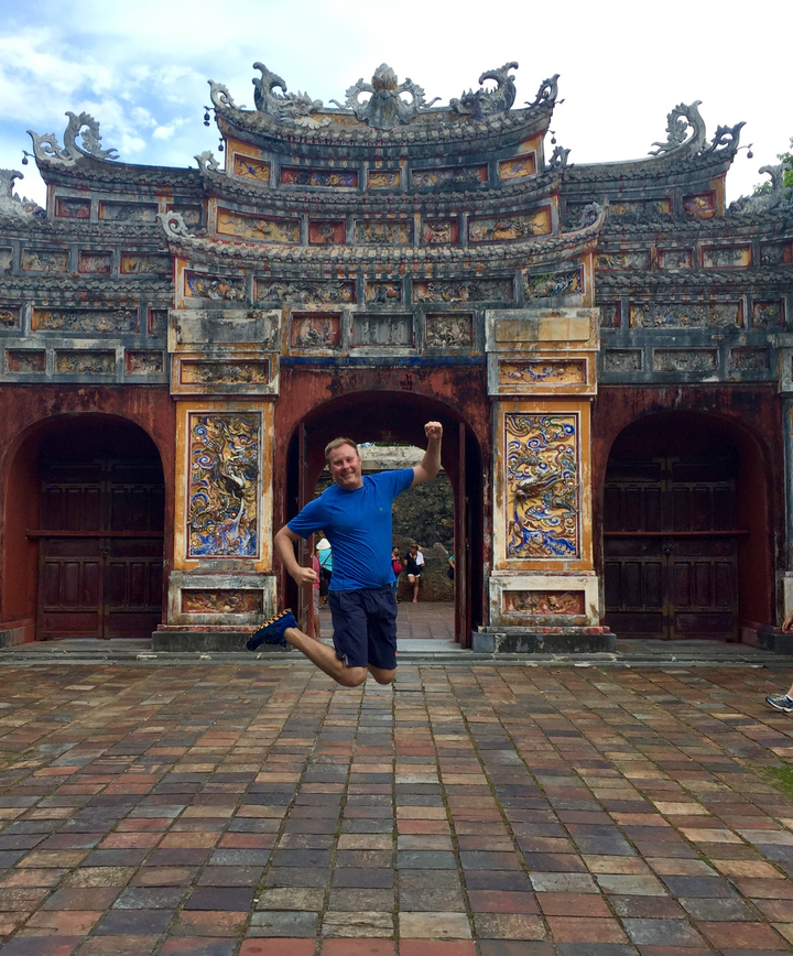 Homme posant joyeusement devant une entrée ornée.