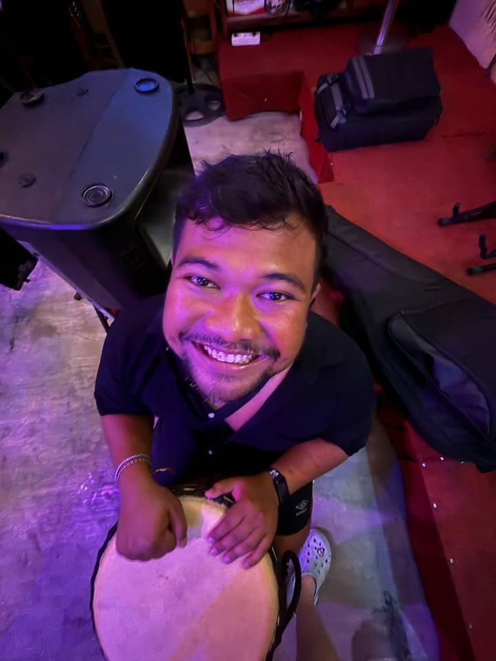 Close-up smiling portrait of a man under colorful club lighting.