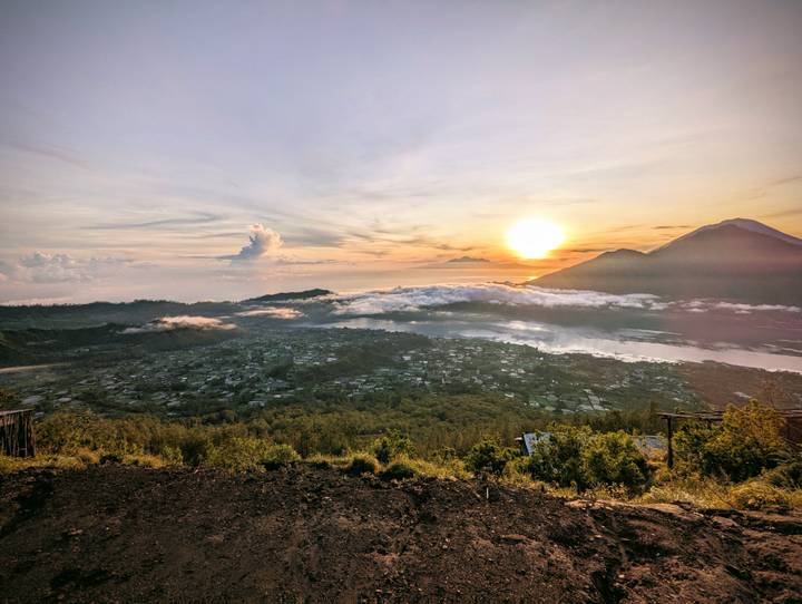 Spectacular sunrise over cloud-shrouded volcanic mountains and a valley village by a lake.