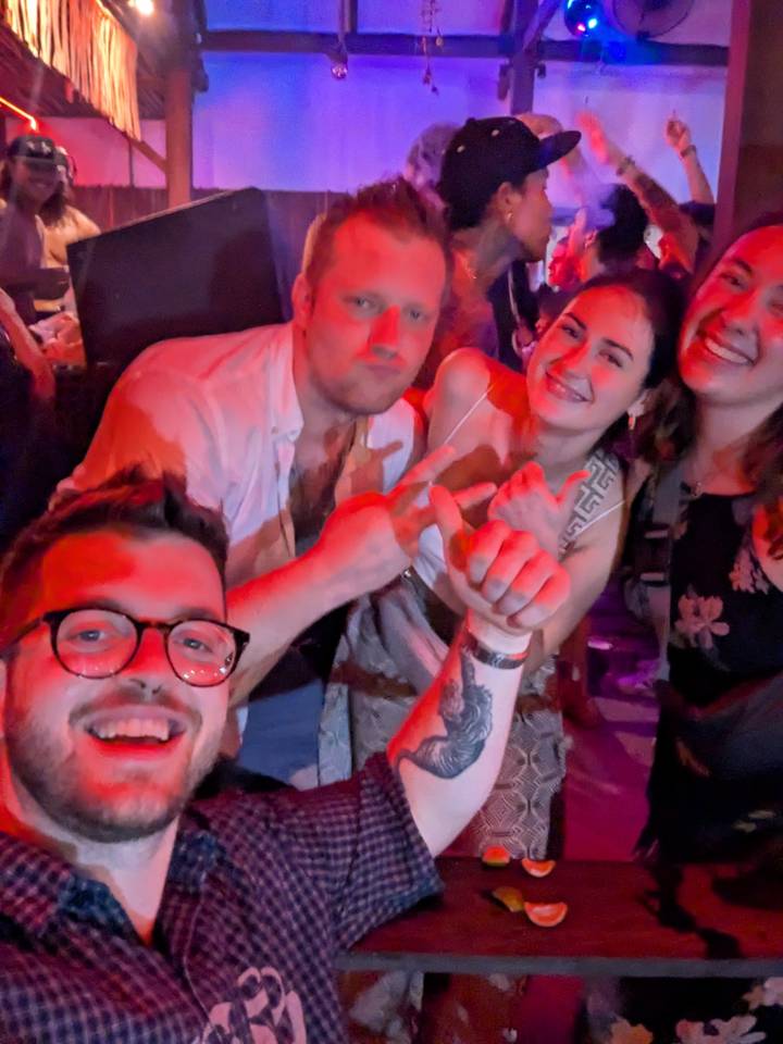 Blurry nightclub selfie of friends dancing under red lights.