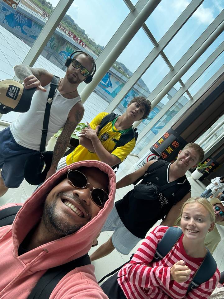Selfie of travelers inside an airport terminal carrying backpacks.