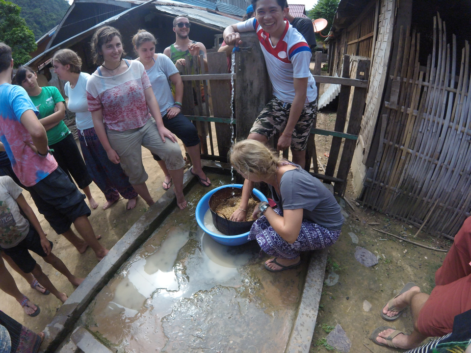 People gathered around an individual working with potting soil.