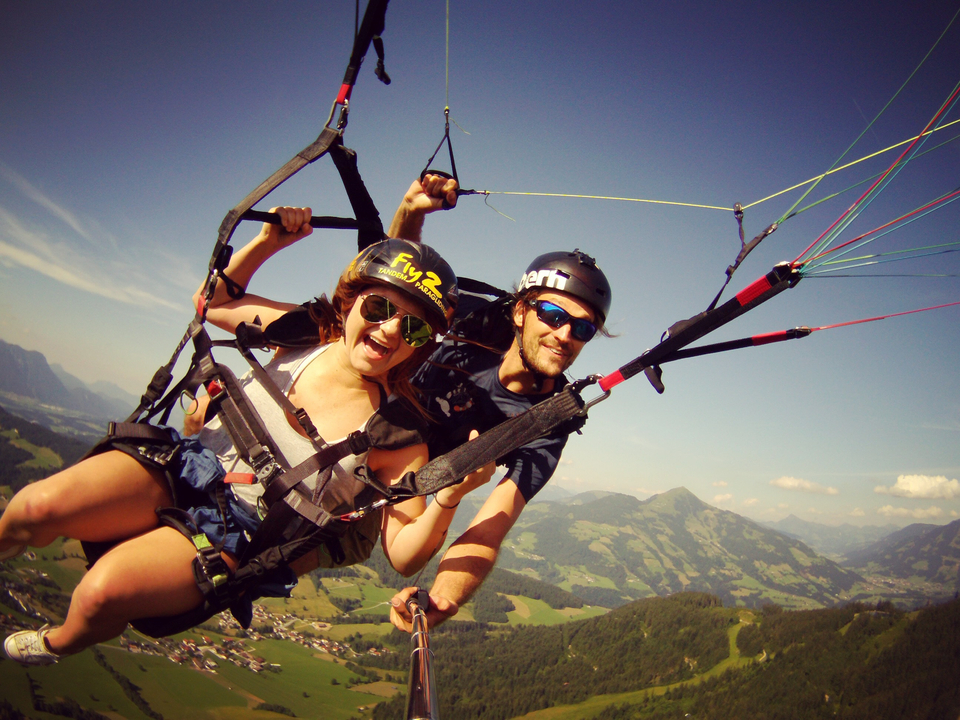 Deux personnes font du parapente sur fond de montagnes pittoresques.