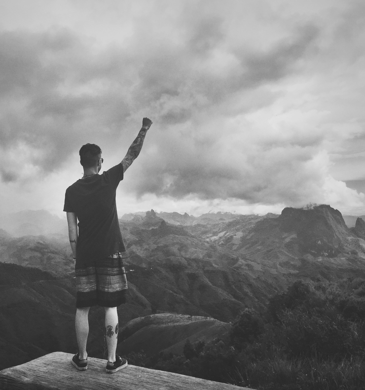 Personne levant le poing au sommet d'une montagne avec des nuages spectaculaires.