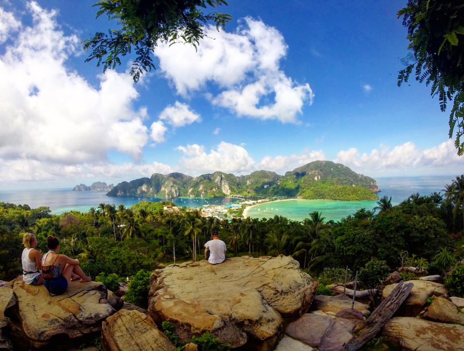 A panoramic view of a tropical beach with people admiring the landscape.