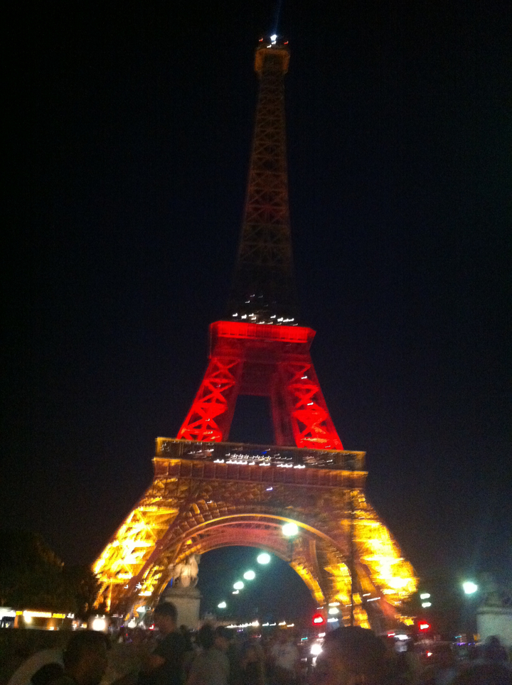 The Eiffel Tower illuminated with red and yellow lights.