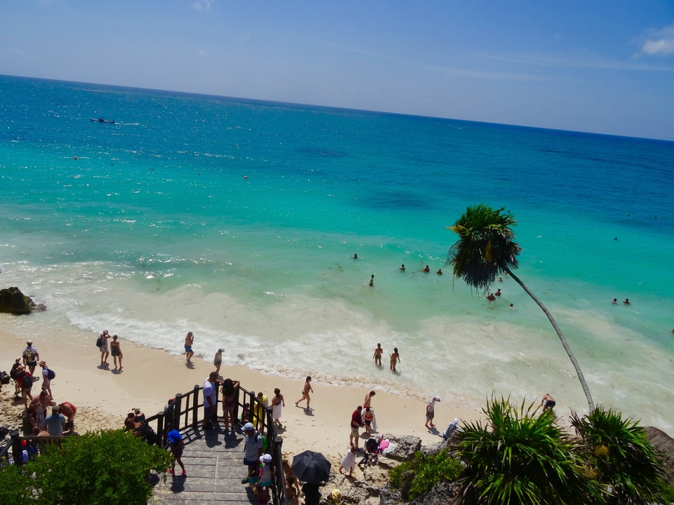 Une plage à l'eau turquoise et des visiteurs qui profitent du soleil.