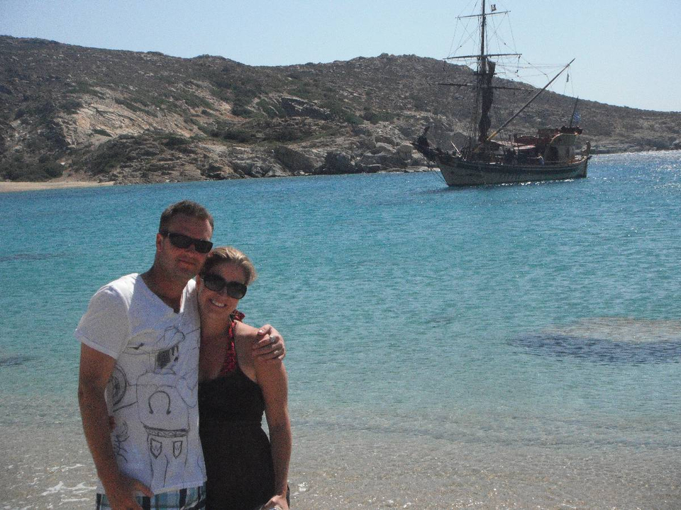Couple standing at the beach with a ship in the background.