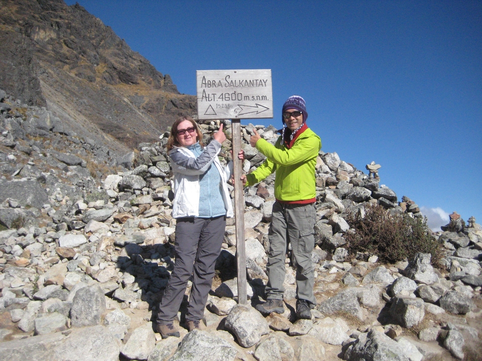 Deux randonneurs pointant du doigt un panneau sur un col de montagne.