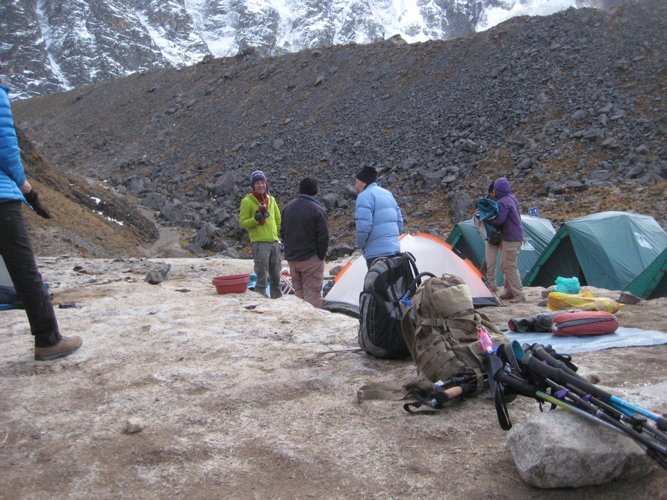 Groupe de personnes dans un camping avec des tentes et des bâtons de randonnée.