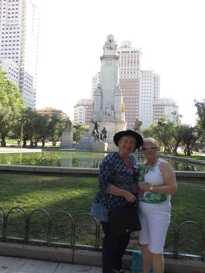 Deux femmes dans un parc avec de grandes statues et un plan d'eau.