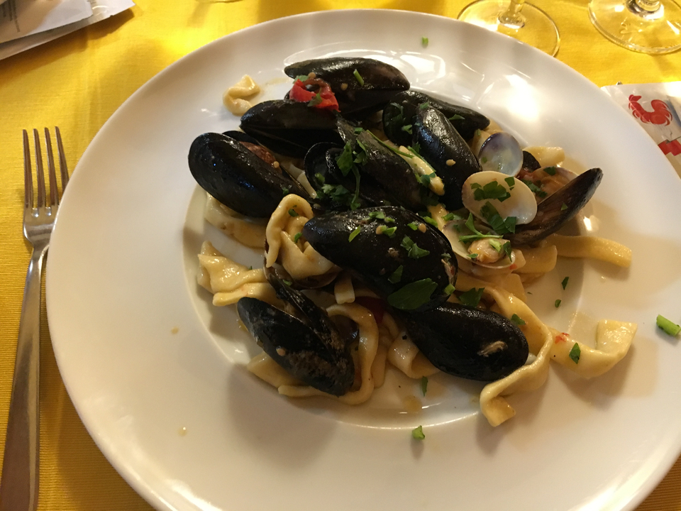 Assiette de pâtes aux fruits de mer avec des moules et une fourchette sur une table.