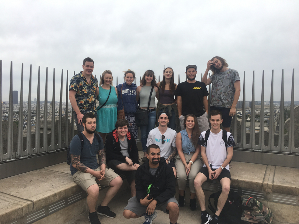 Un groupe de personnes posant pour une photo sur un toit avec la ligne d'horizon de la ville en arrière-plan.
