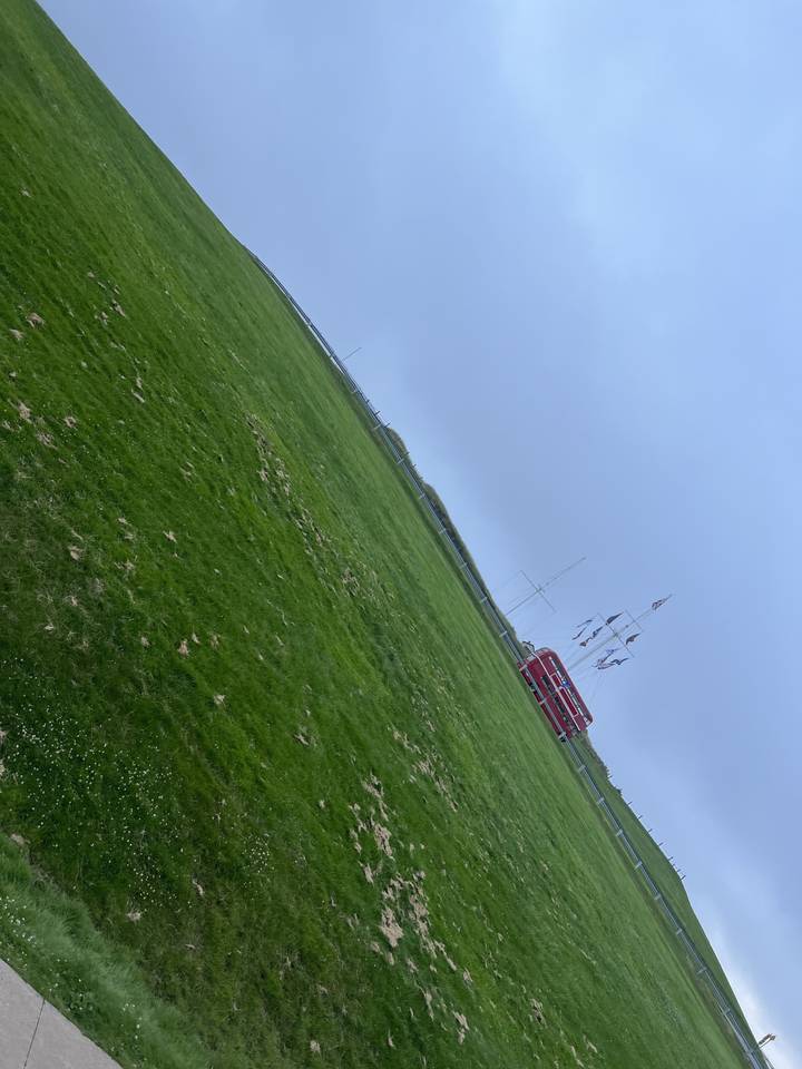 Drapeau et champ ouvert sous un ciel nuageux.