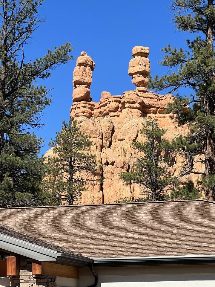 Formations rocheuses verticales avec des arbres sous un ciel dégagé.