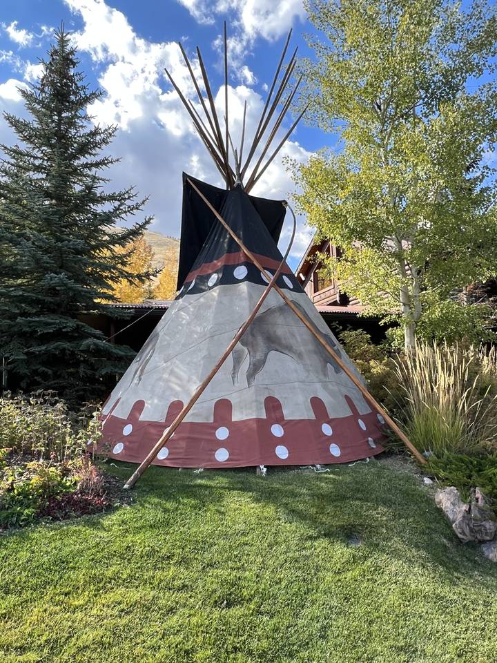 Tipi décoratif installé dans une zone herbeuse.