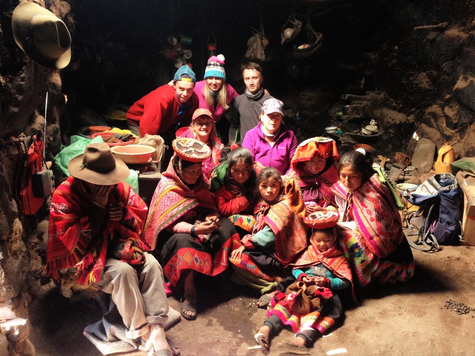 Groupe de personnes en vêtements traditionnels à l'intérieur d'une maison rustique.