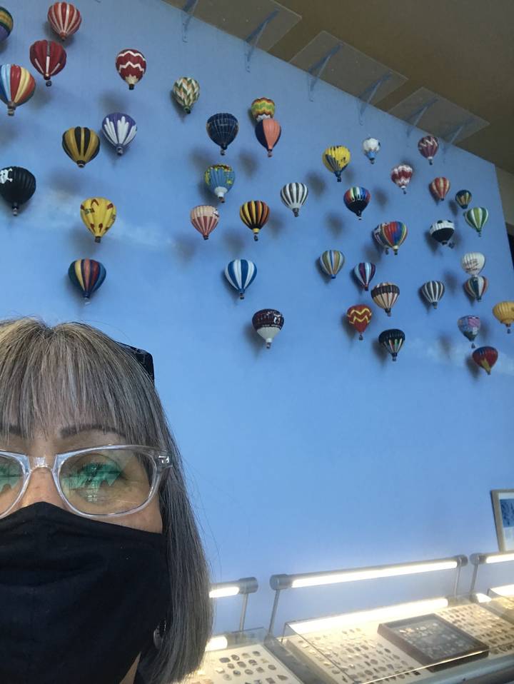 Femme avec des lunettes prenant une photo de modèles de montgolfières sur un mur.