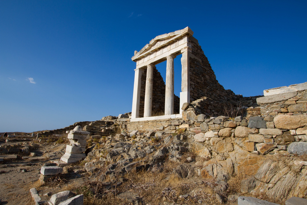 Ancient ruins on a rocky hillside under a clear sky.