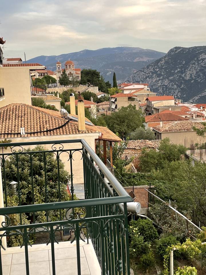 Vue du balcon sur une ville grecque avec des montagnes en arrière-plan.