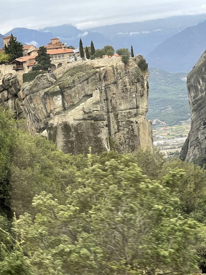 Paysage montrant des formations rocheuses et des structures distantes sur une falaise.