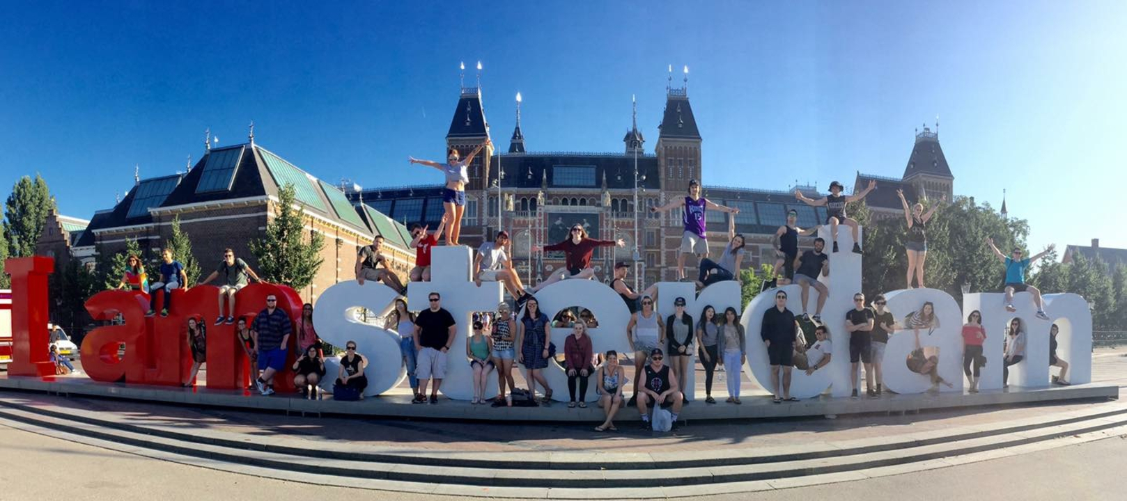 Grand groupe de personnes posant sur les lettres de la ville d'Amsterdam.