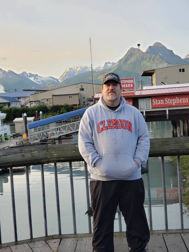 Personne posant sur un quai avec des montagnes au loin.