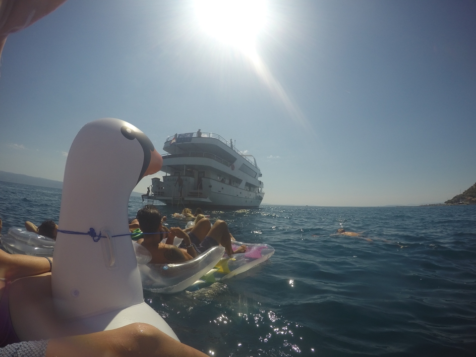 People floating on inflatables near a yacht in the sea.